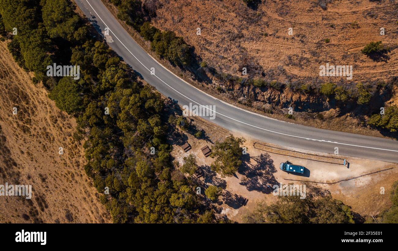 Un colpo d'aria di una strada sulle colline coperte di alberi sotto il sole in Algarve, Portogallo Foto Stock