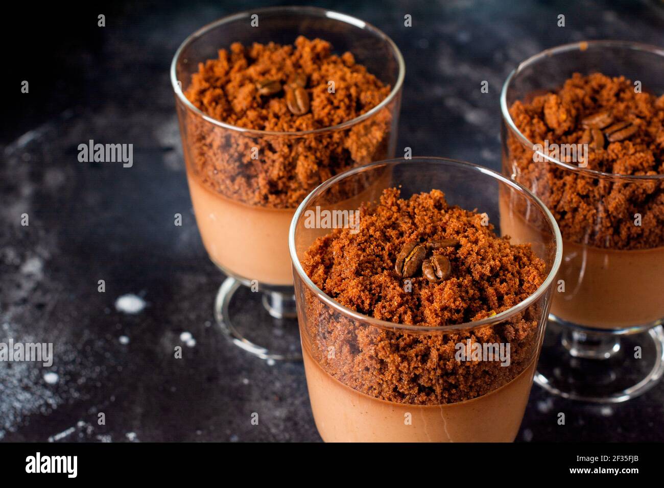 Mousse al cioccolato con brownie in vasi di vetro su un'ardesia scura, pietra o fondo di cemento. Delizioso dessert. Messa a fuoco selettiva. Foto Stock
