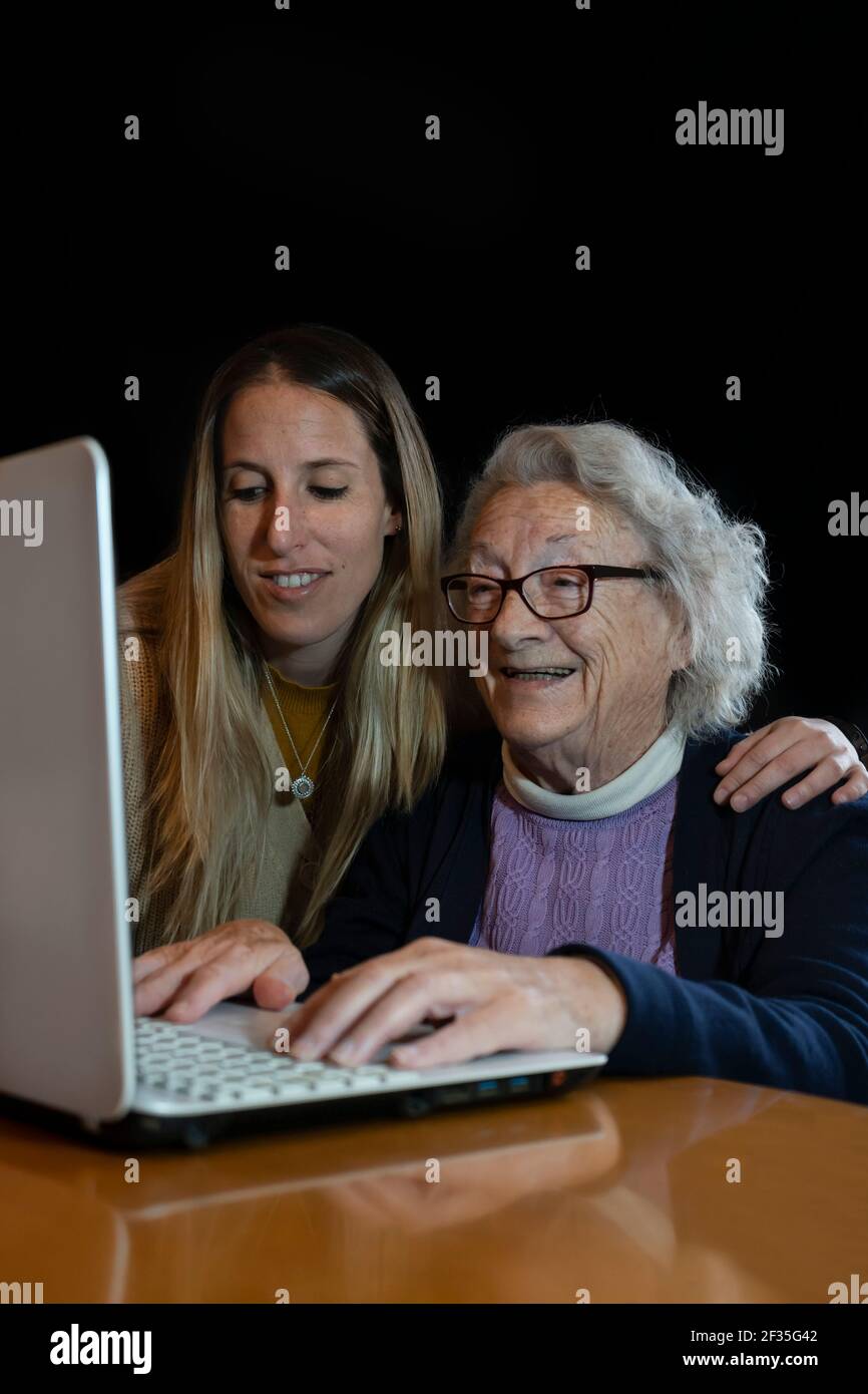 Donna anziana felice degli anni 80 con nipote usando computer.Young aiuto femminile O insegnate a navigare internet nonno.Family divertendosi insieme a guardare v Foto Stock