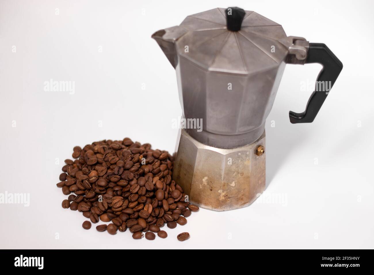 macchina per caffè geyser o caffettiera moka isolata su sfondo bianco con chicchi di caffè nelle vicinanze. Foto Stock