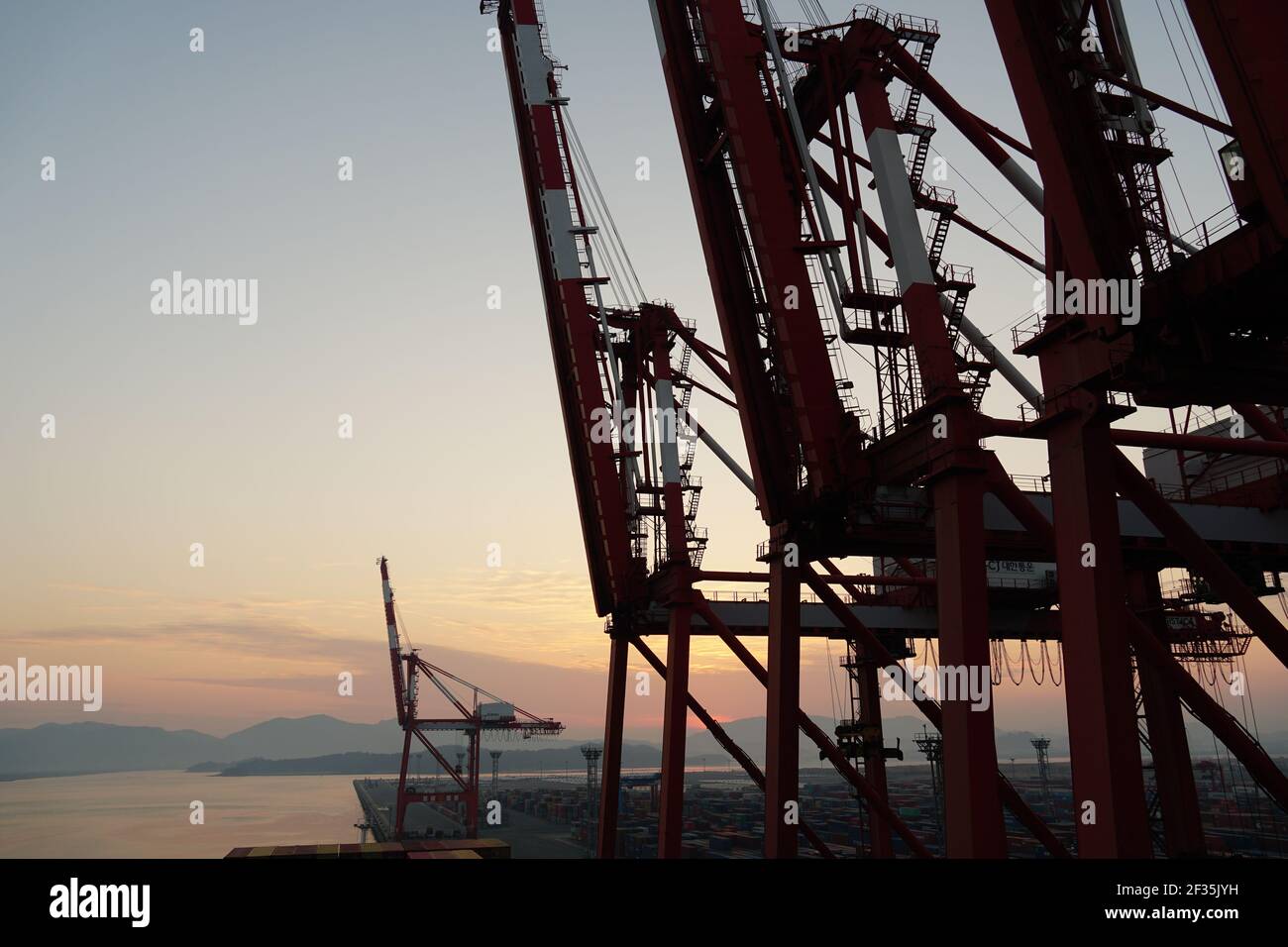 Le gru a gantry durante il tramonto nel terminale del container in attesa del funzionamento del carico. Foto Stock