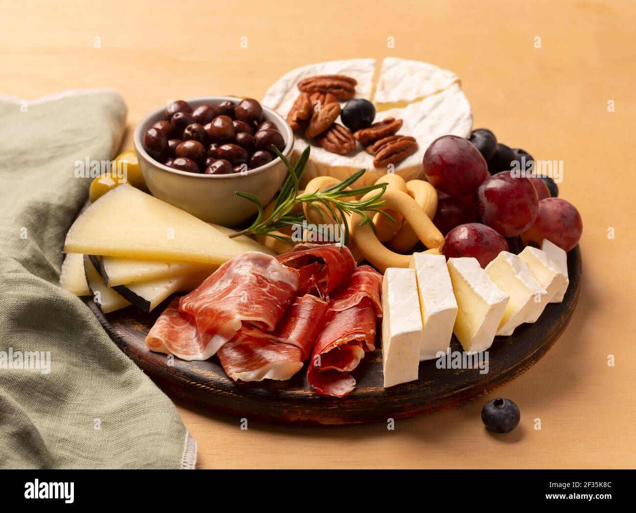 Salumi con jamon spagnolo, salsiccia di maiale con pepe, fuet, formaggio e frutti di bosco su sfondo di legno Foto Stock