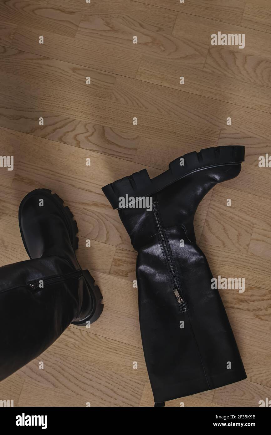 Eleganti stivali in pelle nera sul pavimento. Foto Stock