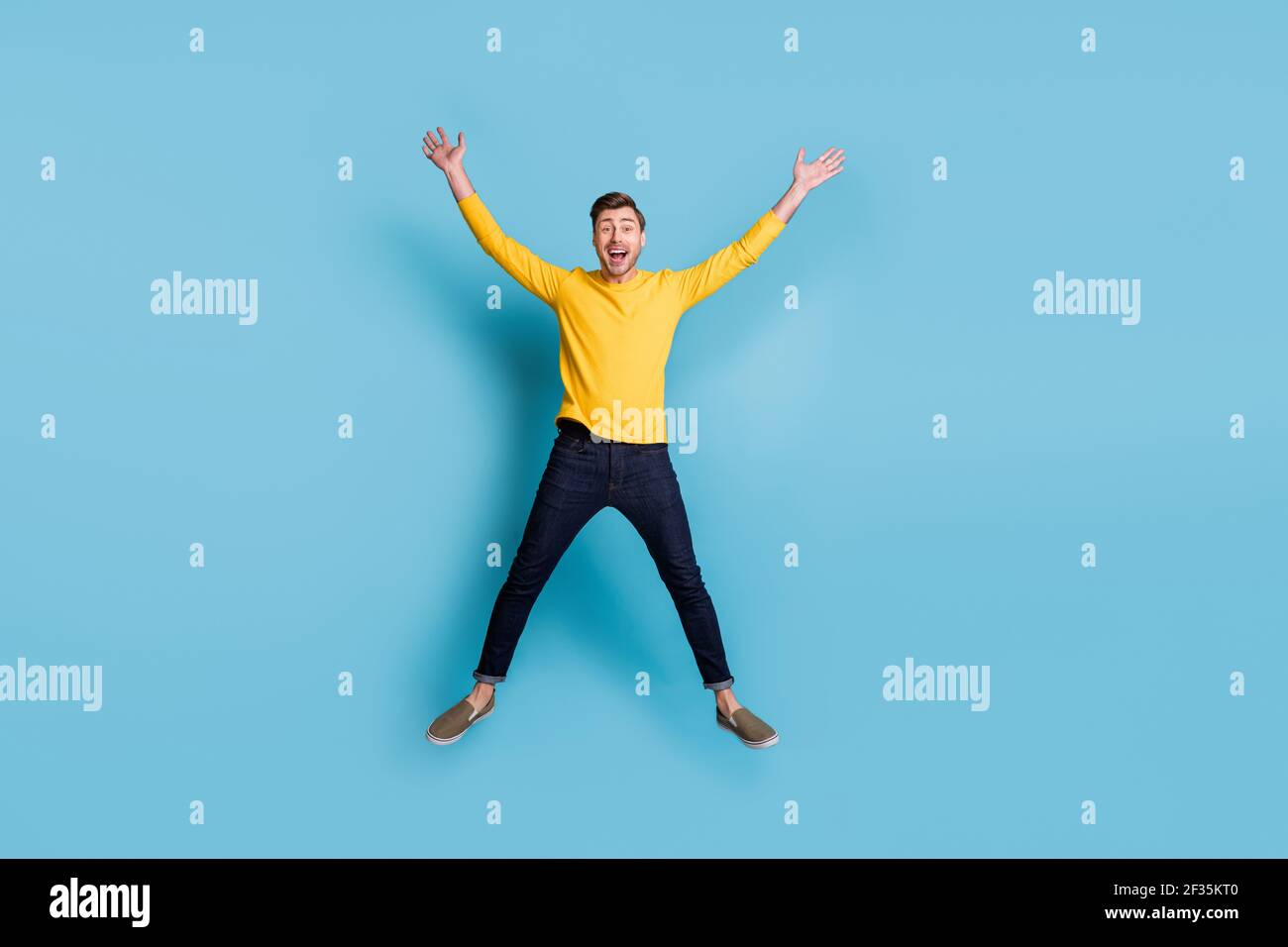 Ritratto di dimensioni complete di un ragazzo sbalordito che salta alto fare la stella figura isolata su sfondo blu Foto Stock