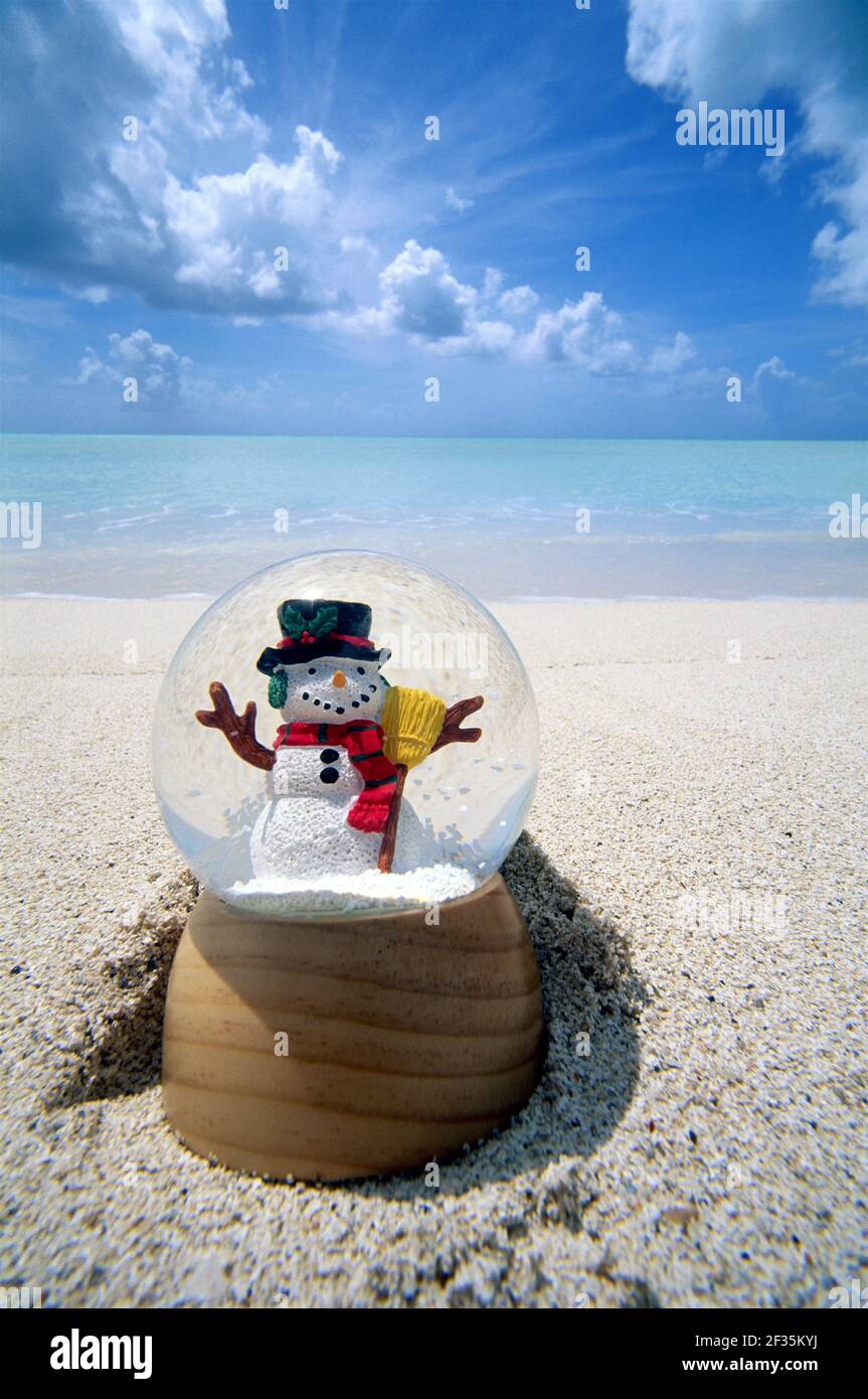 Antigua, Jolly Beach, Snowglobo con pupazzo di neve sulla spiaggia al bordo dei surfs con acqua e cielo che raffigurano inverno scappare Foto Stock