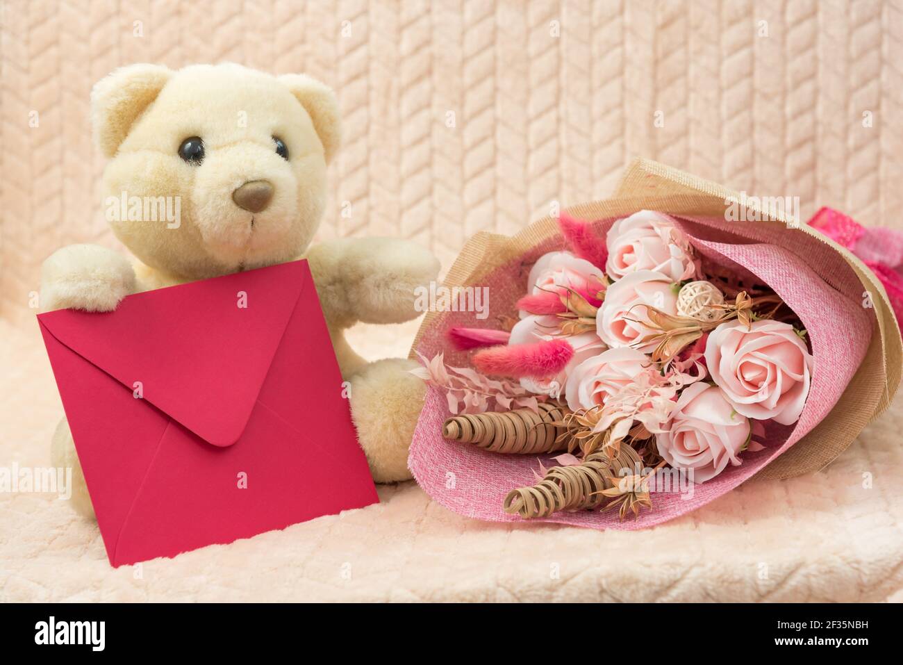 Orsacchiotto polare giocattolo imbottito con fiori e busta rossa con Complimenti. Il concetto di una vacanza per bambini, mamme giorno, compleanno Foto Stock