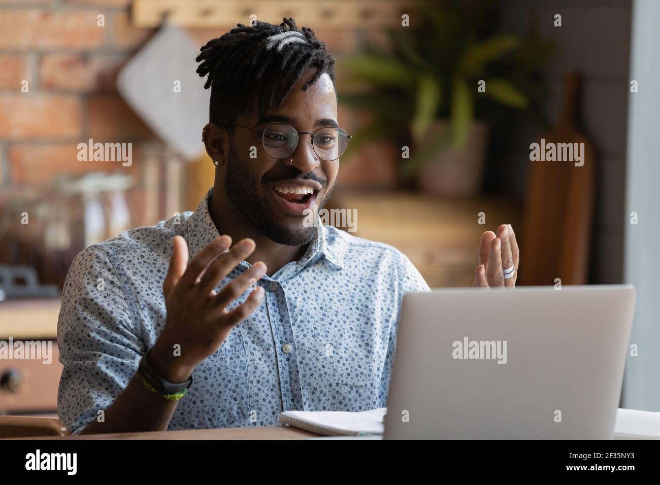 Un giovane ragazzo nero che si è divertito a schizzare le mani guardando lo schermo del computer portatile Foto Stock