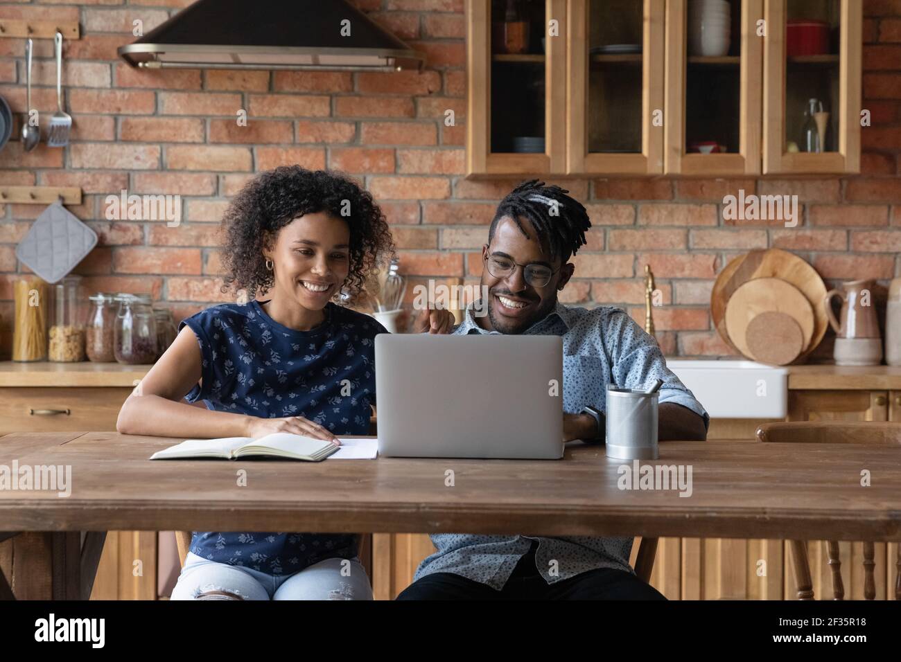 Amico afro americano sposato studio di coppia da casa utilizzando il computer portatile Foto Stock