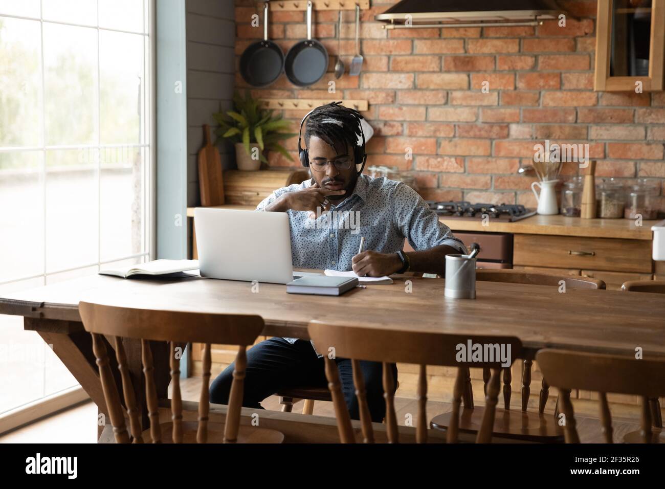 Giovane ragazzo nero che impara da casa utilizzando il laptop e le cuffie Foto Stock