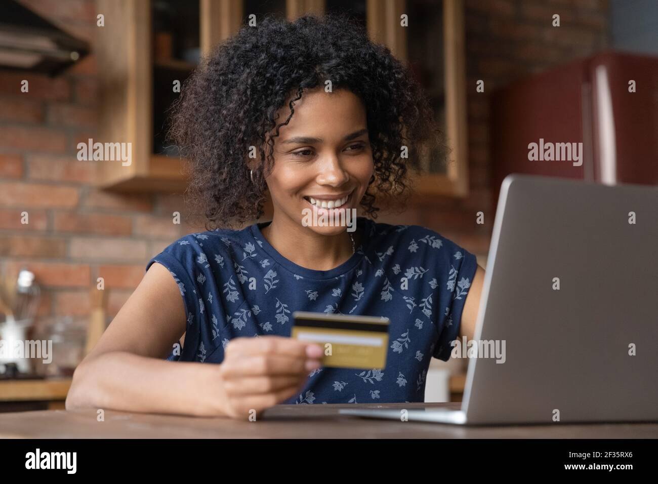 Happy biracial femmina acquistare merci su internet utilizzando la carta oro Foto Stock