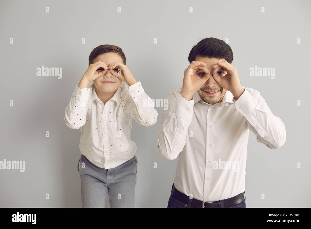 Il padre allegro ed il figlio piccolo guardano in binocoli immaginari fatti delle loro mani. Foto Stock