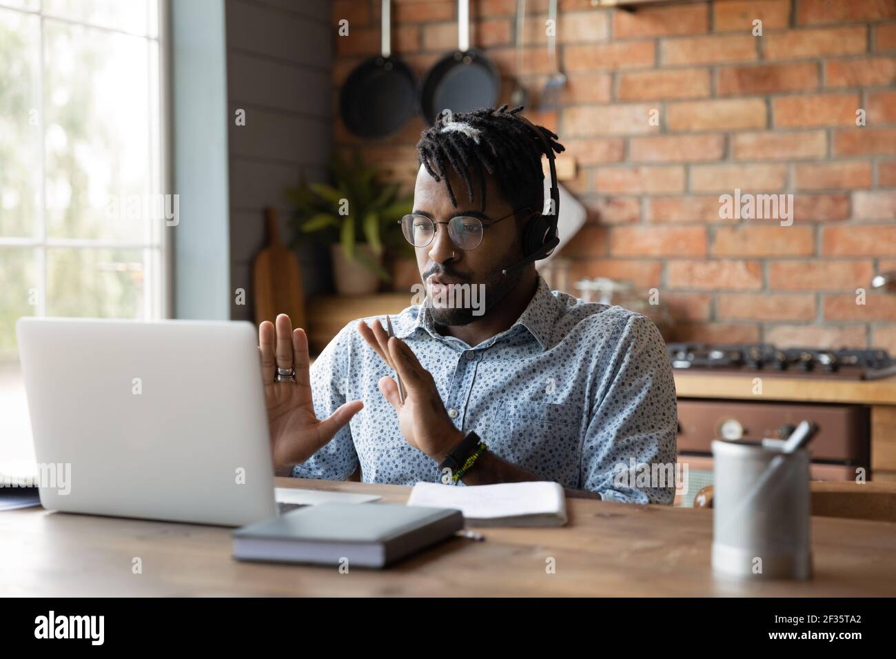 Black man esperto in cuffie assistere il cliente online utilizzando il computer portatile Foto Stock