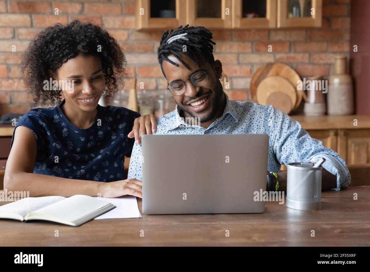 Sorridente nero marito guardare sullo schermo del computer portatile consultare con la moglie Foto Stock