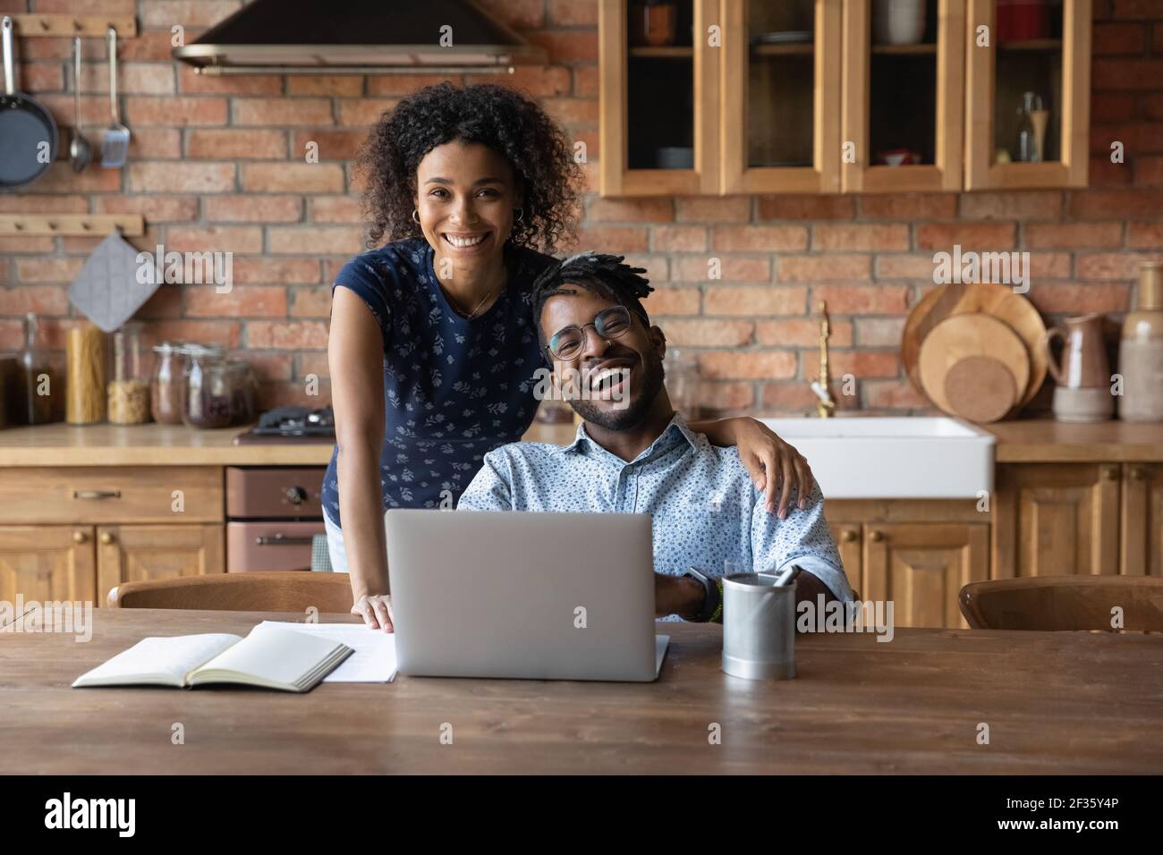 Felice famiglia africana giorno moderno coppia utilizzando il computer portatile in cucina Foto Stock