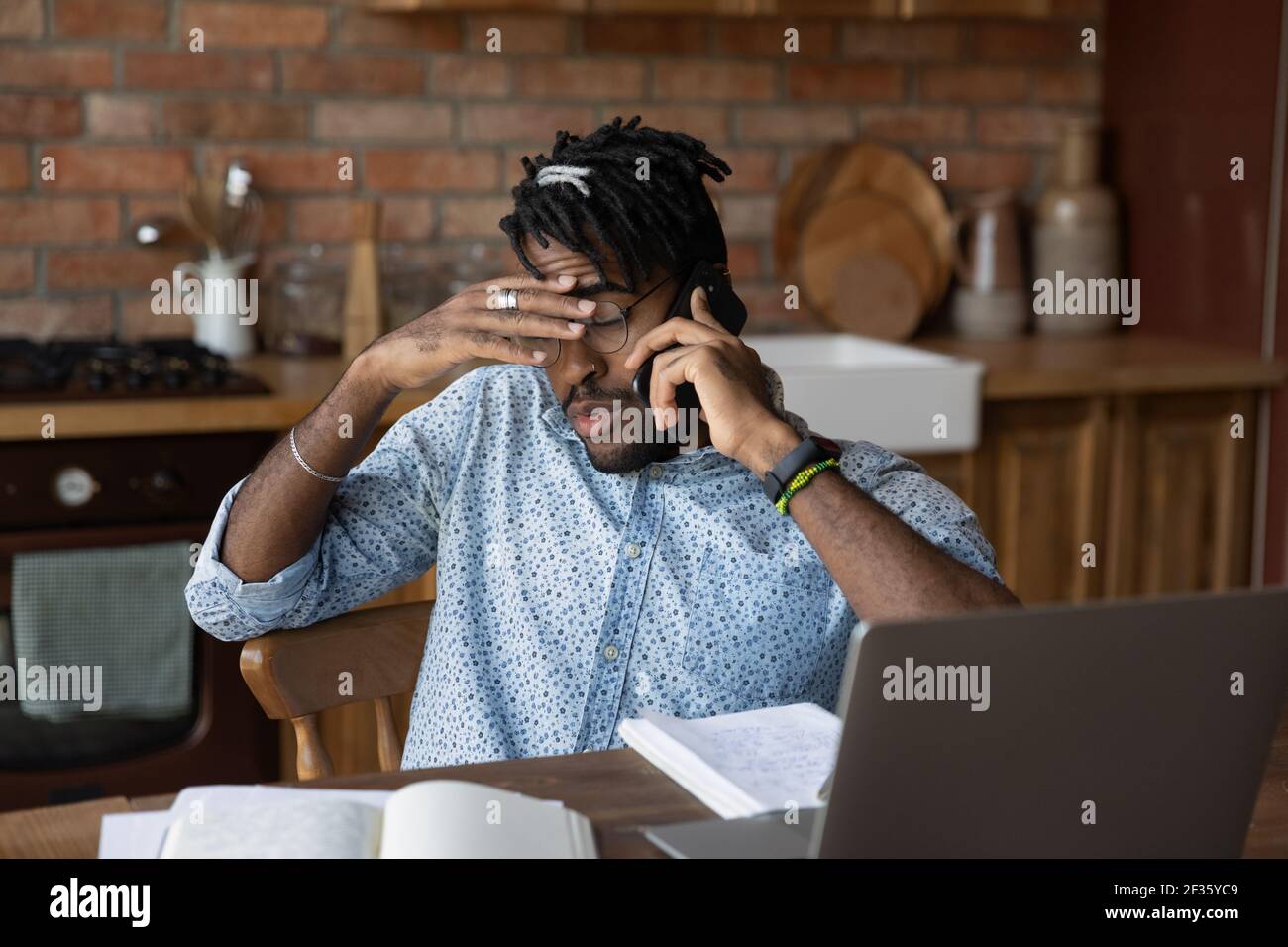 Uomo nero stanco freelance impegnato in multitasking Feel informazioni sovraccarico Foto Stock