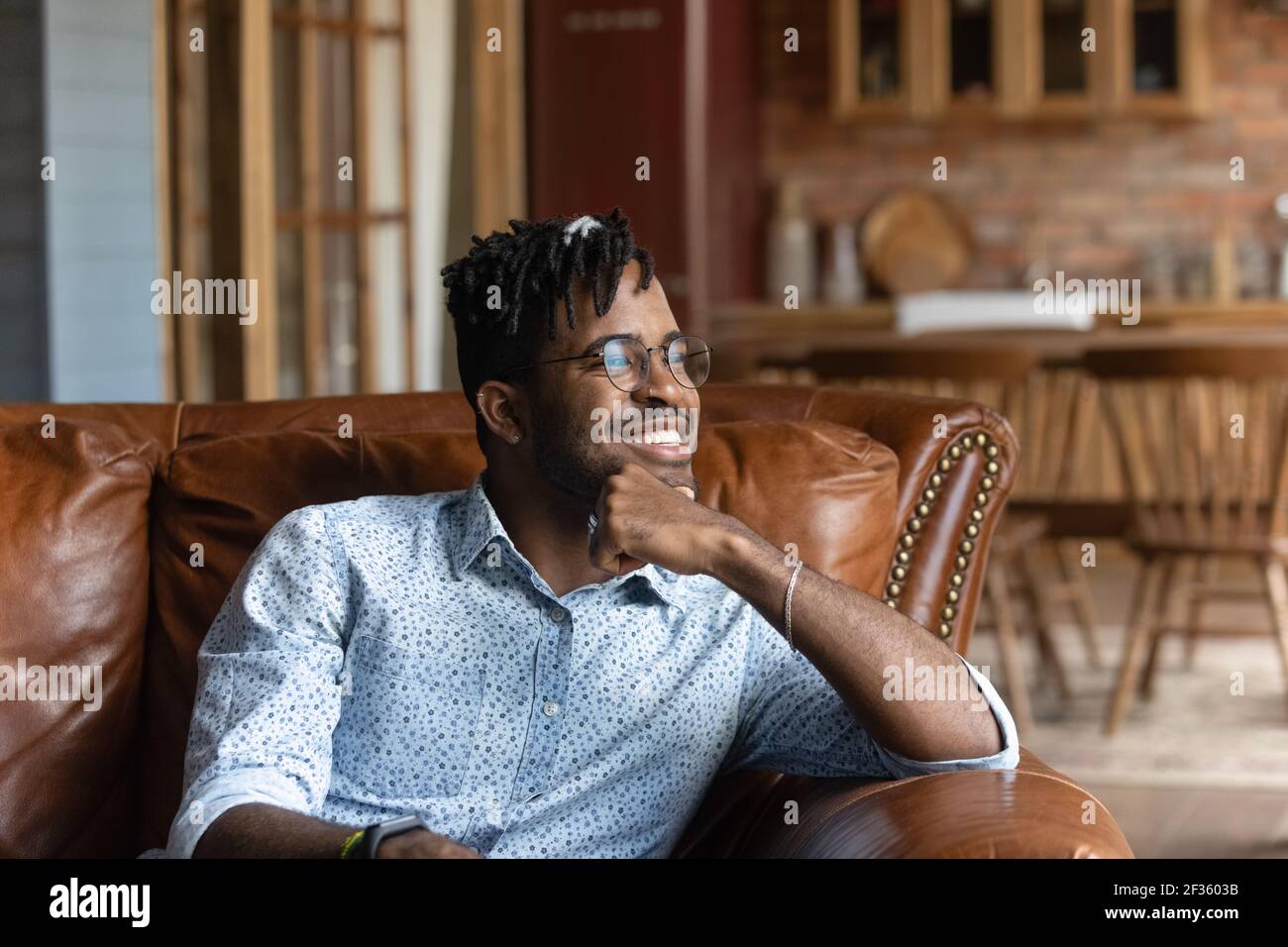 Felice giovane africano uomo rilassarsi sul divano godersi una buona giornata Foto Stock