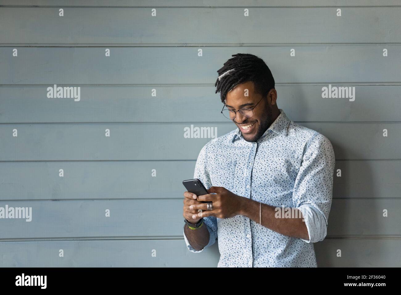 Sorridente giovane hipster nero maschio godere di internet surf su cella Foto Stock