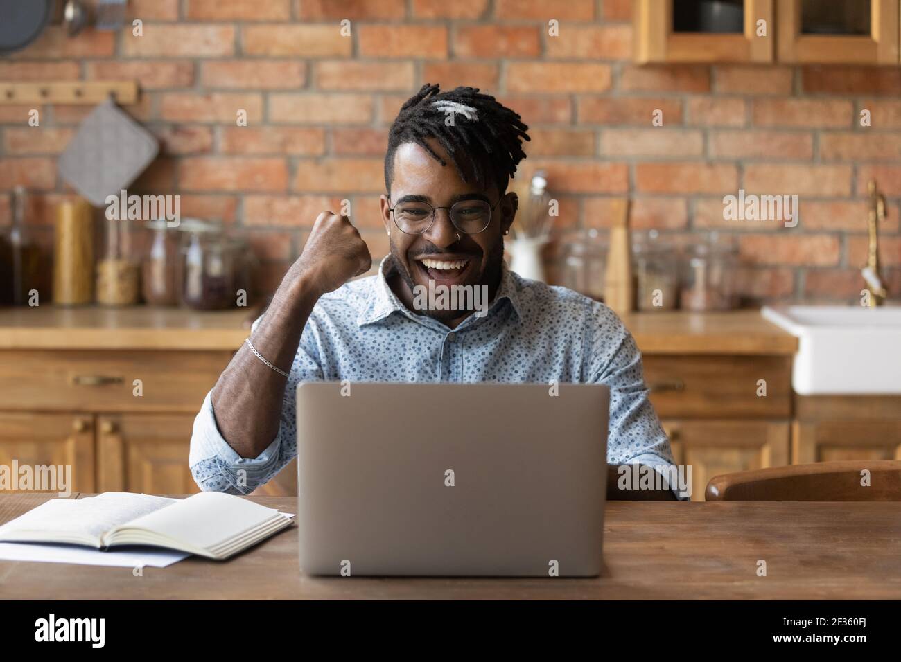 Allievo del ragazzo nero eccitato che vede il buon risultato dell'esame sul laptop Foto Stock