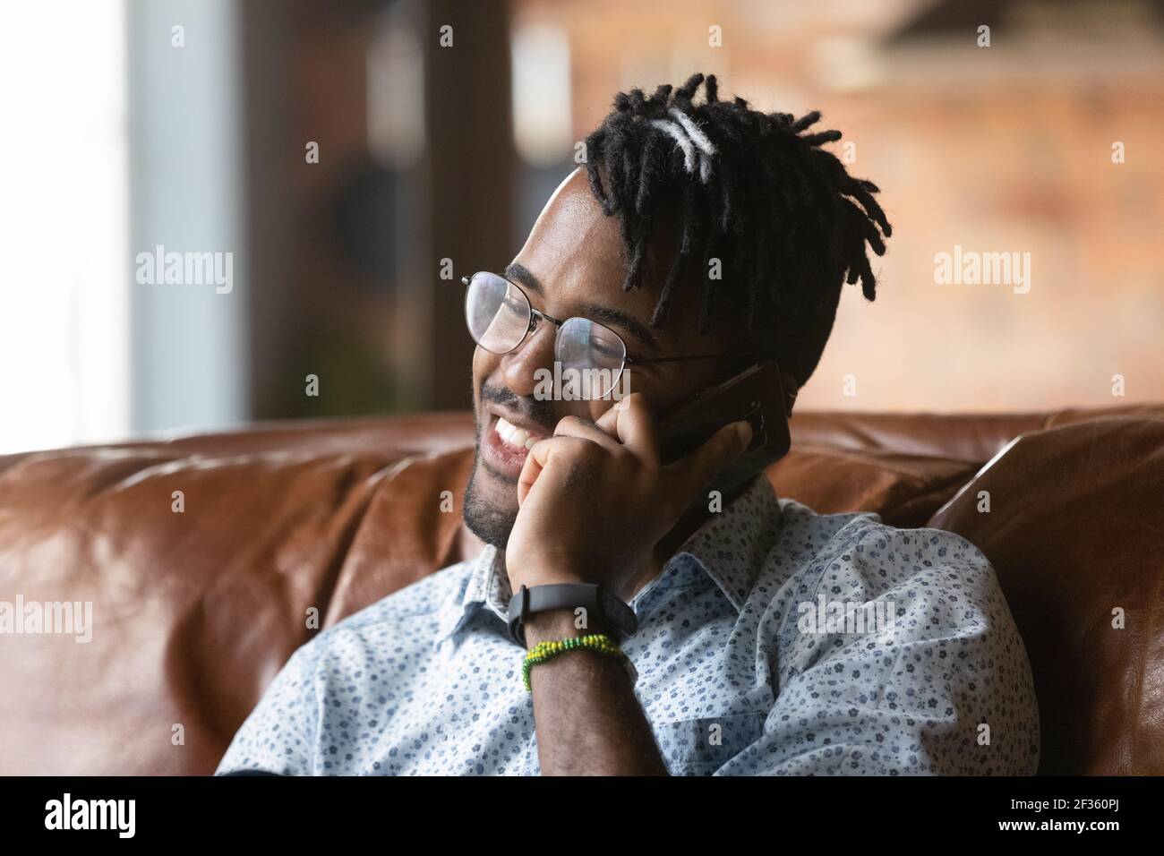 Hipster maschile afroamericano positivo millennial chiamando amico per telefono Foto Stock