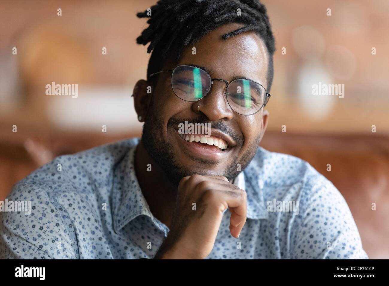 Il giovane maschio africano in occhiali mostra denti forti nel sorriso Foto Stock