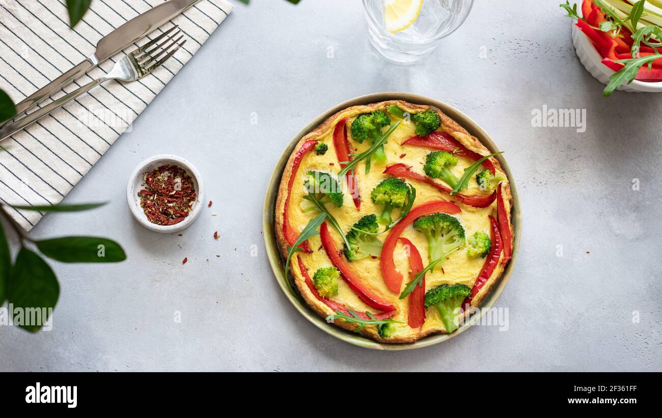 gustosa frittata con broccoli e peperone dolce su fondo grigio in cemento. vista dall'alto, banner, posto per il testo. Foto Stock