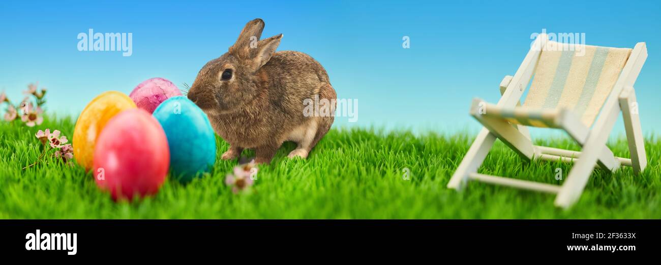 Concetto di vacanze di Pasqua con uova di Pasqua e sedia a sdraio un prato verde Foto Stock