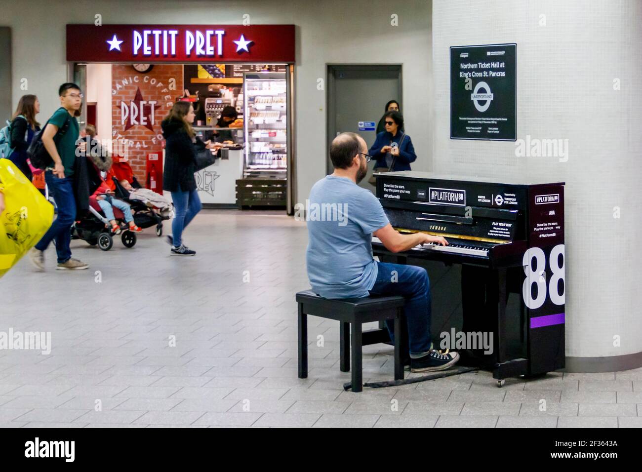 Un membro del pubblico che suona un pianoforte verticale nella biglietteria della stazione della metropolitana King's Cross, Londra, UK Foto Stock