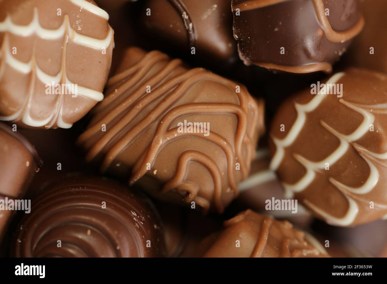 Set di cioccolatini, dolci al cioccolato, motivo di cioccolato. Primo piano con caramelle su sfondo marrone. Cioccolatini al latte scuro. Set di cioccolatini diversi. Dolci Foto Stock