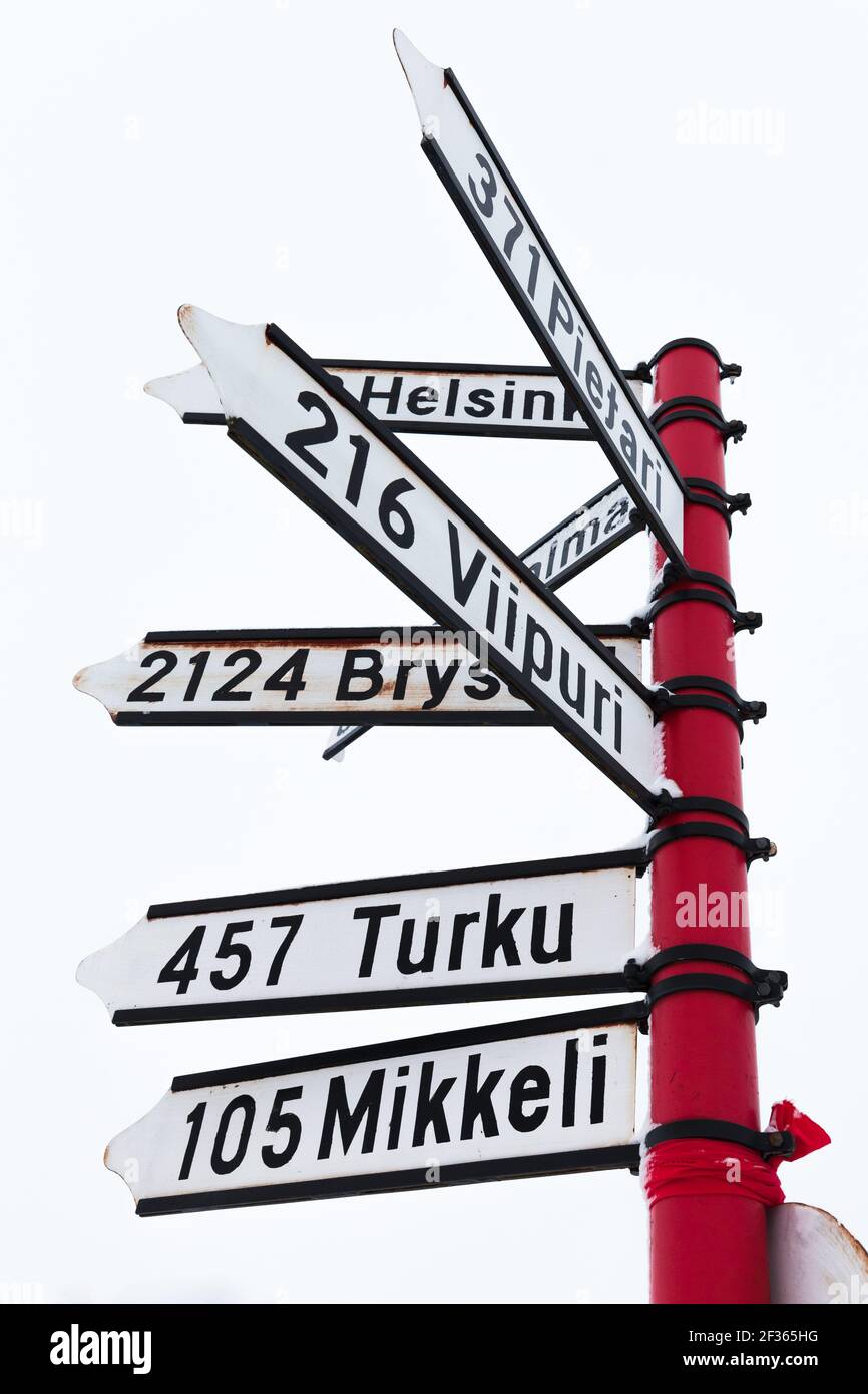Il cartello con le distanze per le città finlandesi è sotto il cielo luminoso di giorno Foto Stock