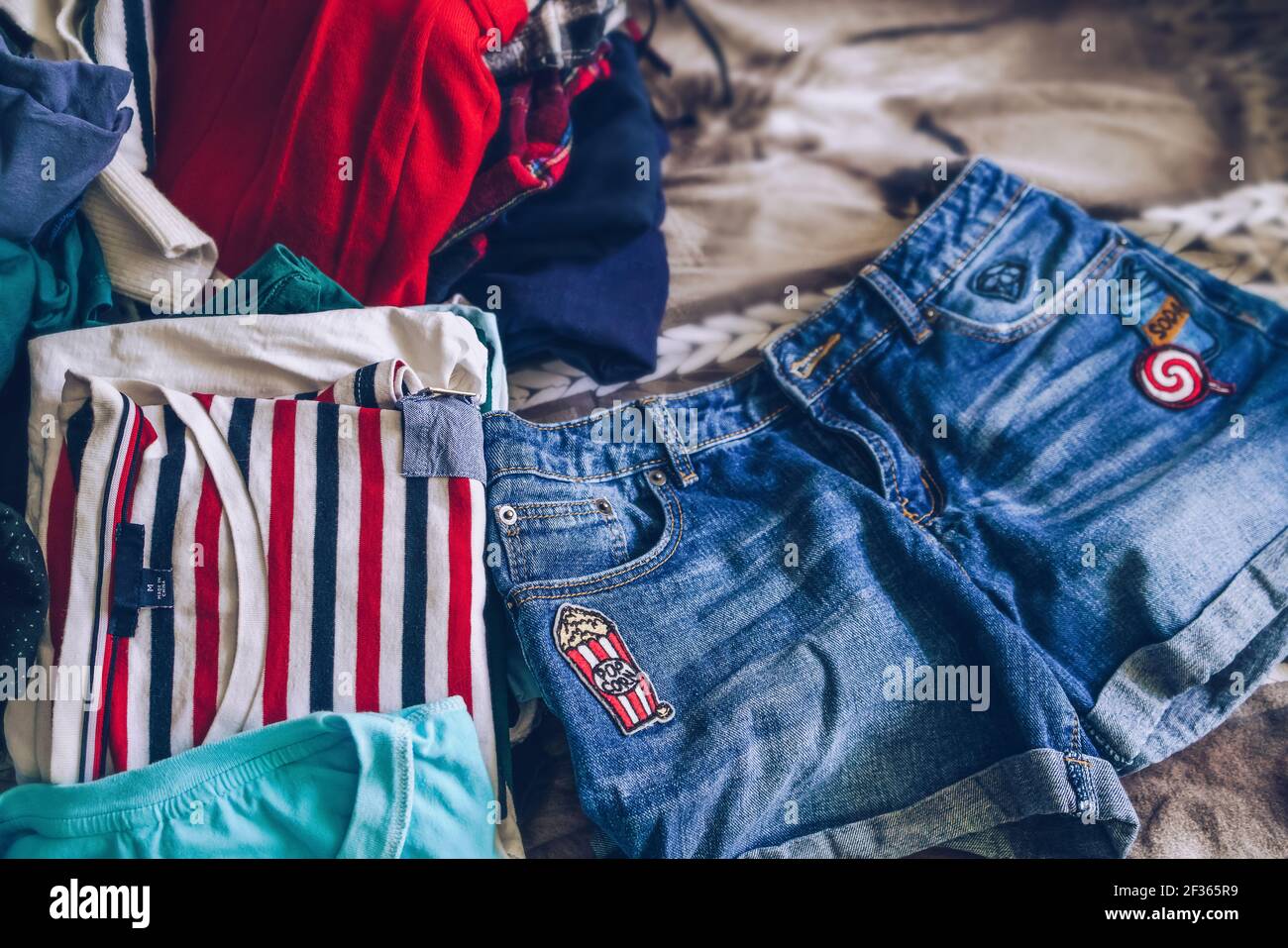 scelta del concetto di vestiti con il mucchio sudicio sullo sfondo e jeans shorts davanti Foto Stock