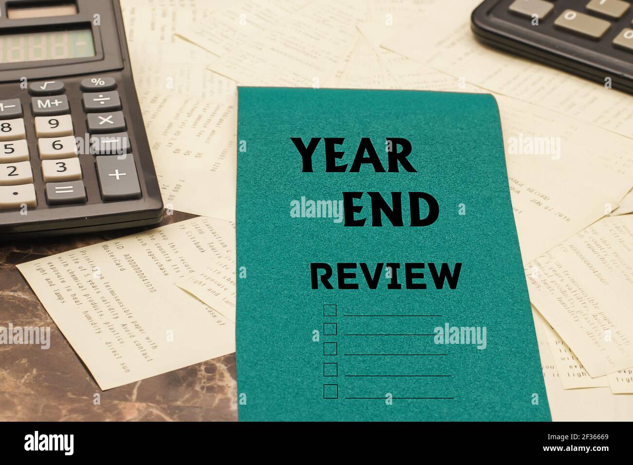 TESTO DI REVISIONE DI FINE ANNO su un pezzo di carta blu su una scrivania, accanto alle calcolatrici nere e a molti controlli, concetto di valutazione annuale del Th Foto Stock
