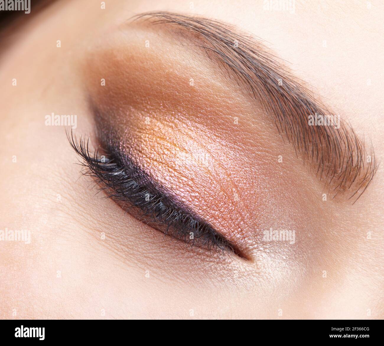 Macro shot closeup dell'occhio femminile chiuso. Donna con naturale sera Vogue viso bellezza trucco. Ragazza con pelle perfetta e occhi rosa ombre. Foto Stock