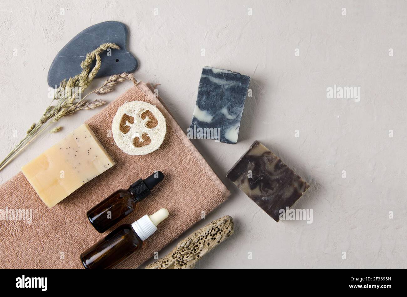 Accessori cosmetici per la cura del corpo, della mano, del viso. Sulla salvietta si trova sapone naturale, siero naturale in bottiglie di vetro con una pipetta, guache di pietra naturale, A. Foto Stock