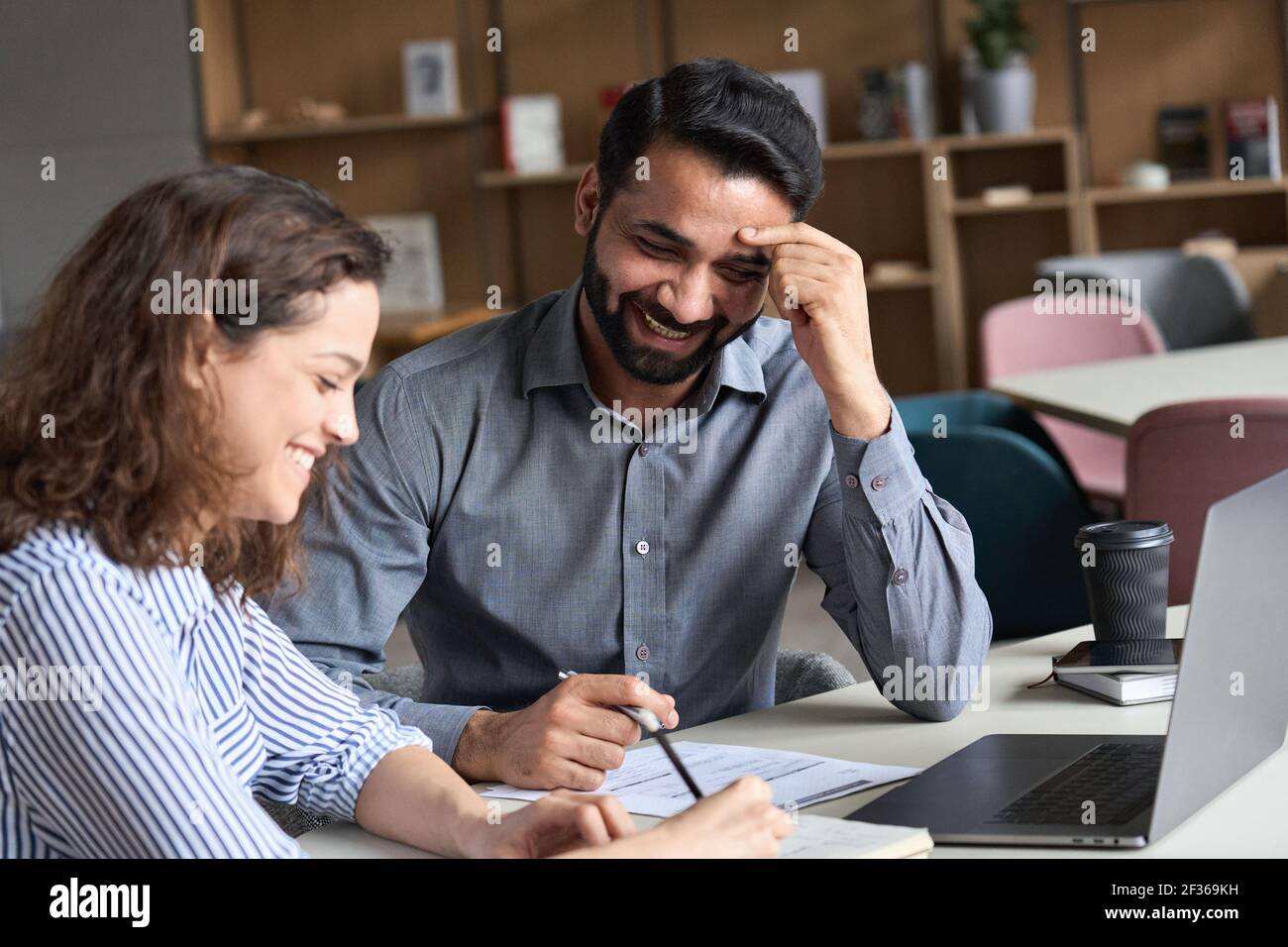 Due dipendenti professionali felici e cordiali che discutano sul posto di lavoro. Foto Stock