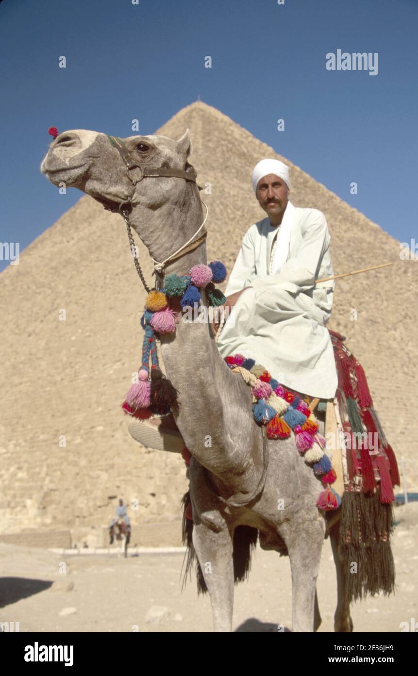 Cairo Egitto Giza Egiziano Distretto Grande Piramide di Kheops, costruito 2600 a.C. a.C. sette meraviglie del mondo, uomo musulmano cammello rider che offre giostre, Foto Stock