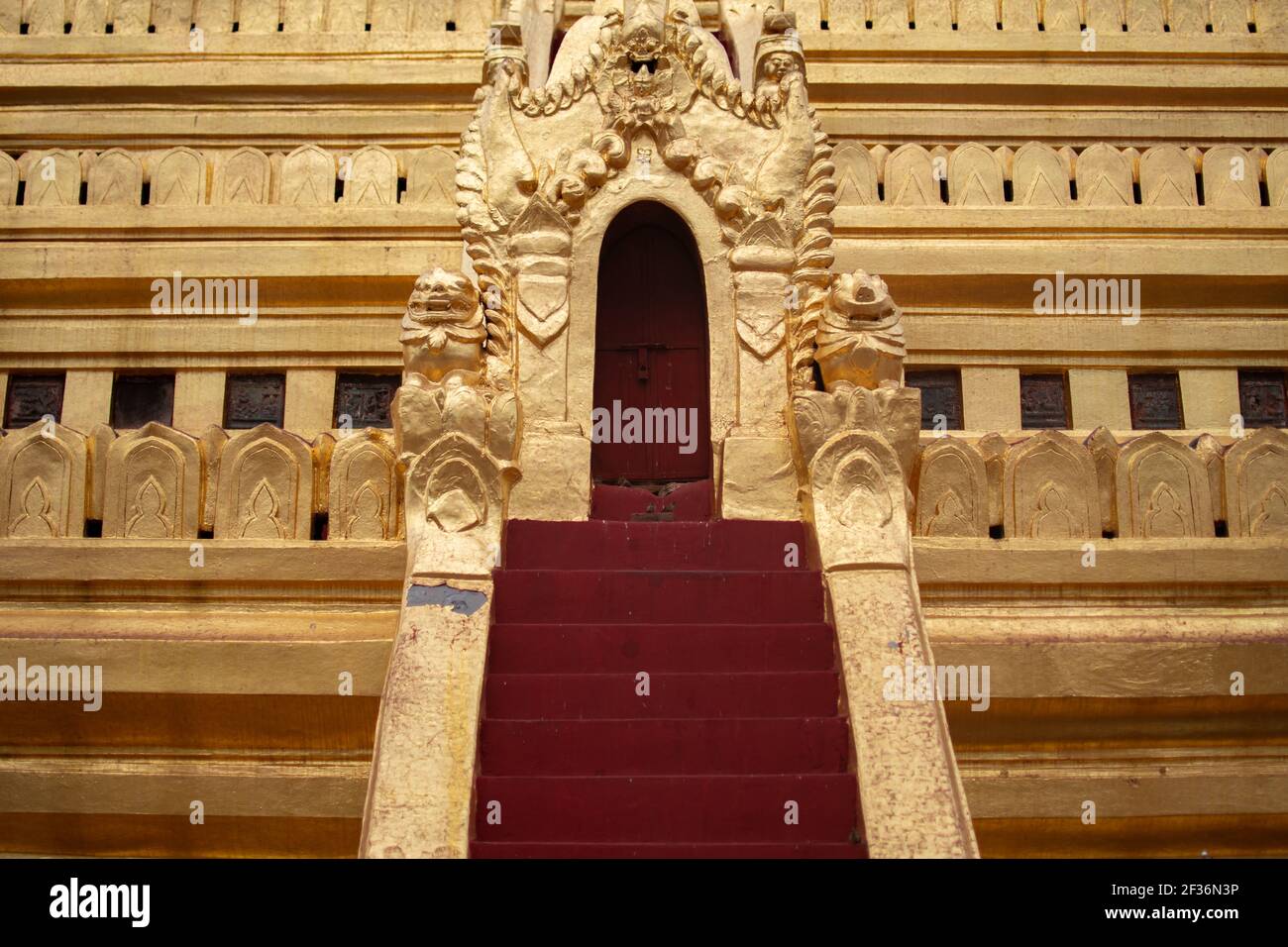 BAGAN, NYAUNG-U, MYANMAR - 2 GENNAIO 2020: Un ingresso con scale rosse e una porta rossa a una famosa pagoda di stupa dorata Foto Stock