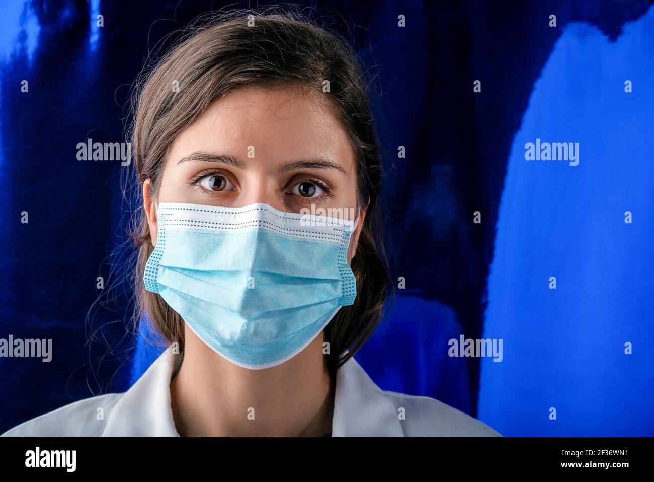Giovane infermiera che guarda la macchina fotografica che indossa la maschera chirurgica covid protezione Foto Stock