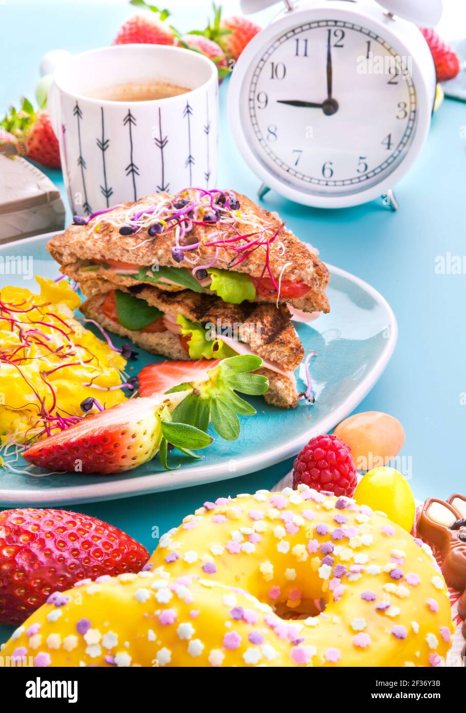 Ottimo cibo per colazione e ciambelle dolci pane tostato con prosciutto, insalata e scramble, cosparso di semi germogliati, un piatto di cereali con frutti di bosco, super cibo . Deliziosa colazione sana Foto Stock