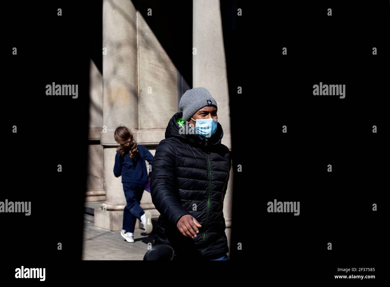 Uomo che indossa maschera a piedi brissamente in strada, Barcellona, Spagna. Foto Stock