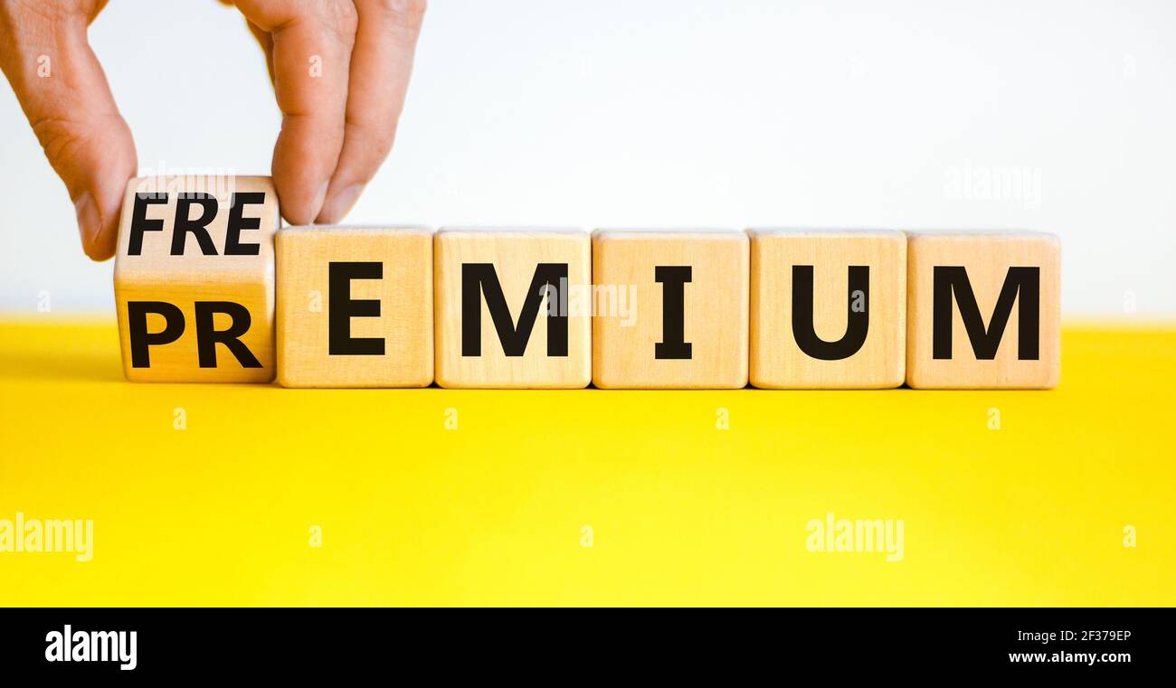 Simbolo Premium o freemium. Uomo d'affari trasforma il cubo di legno, cambia la parola 'premium' in 'freemium'. Bel tavolo giallo, sfondo bianco. Autobus Foto Stock