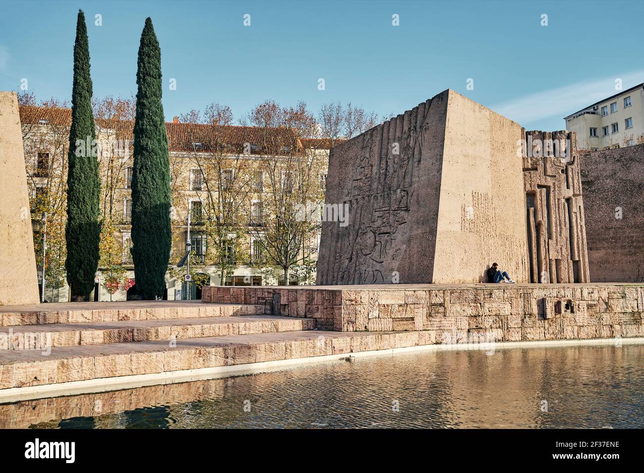 Uomo seduto vicino al monumento sul terrapieno Foto Stock