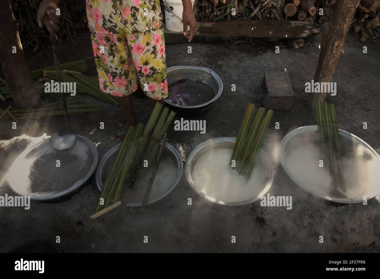 Una donna che bolle la palma sap per fare lo zucchero di palma, una fonte alternativa di reddito per gli abitanti di un villaggio che vivono a Rote Island, Indonesia. Foto Stock