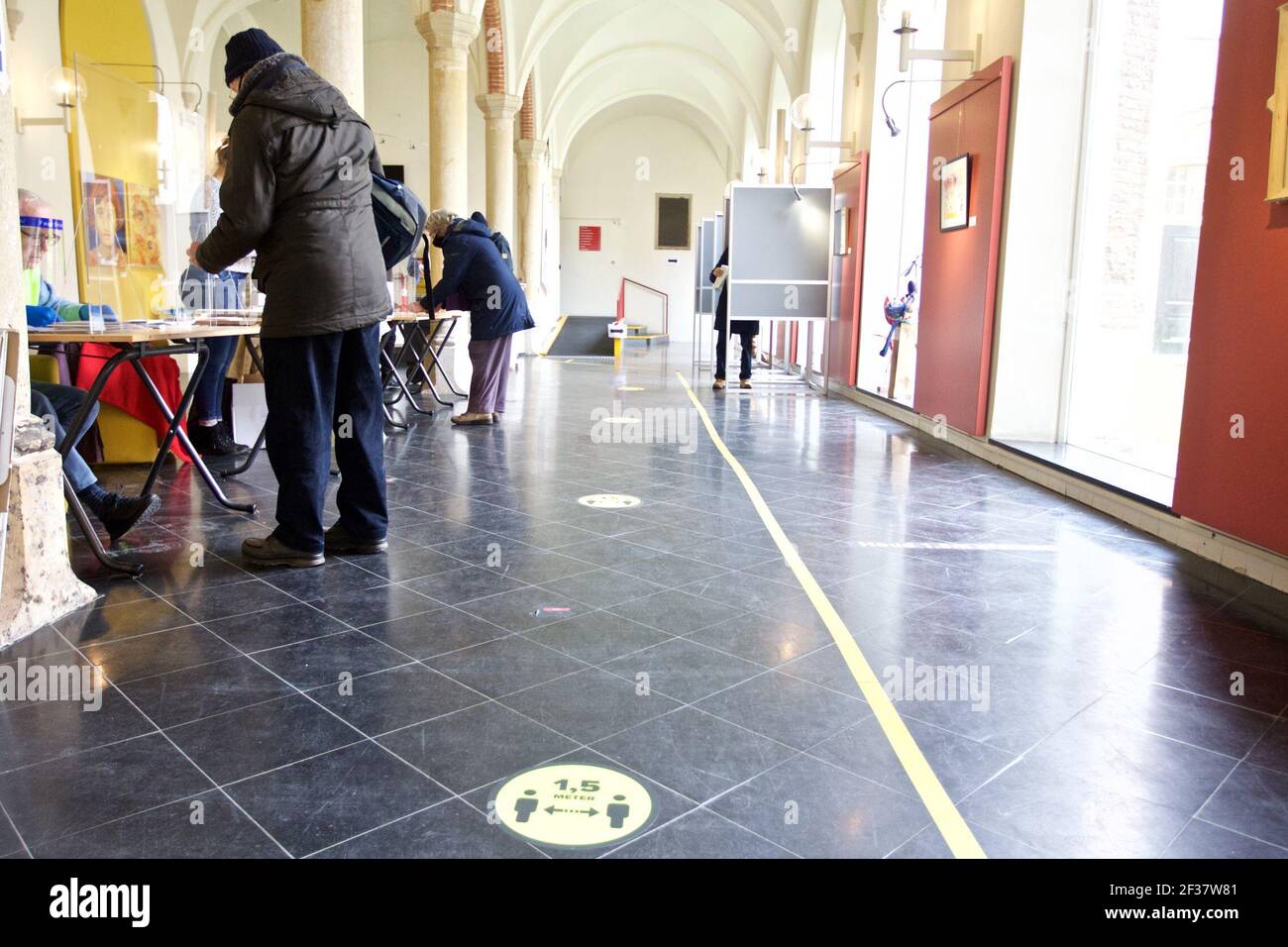 Haarlem, Paesi Bassi. 15 marzo 2021. La gente si registra per votare in una stazione di voto a Haarlem, Paesi Bassi, il 15 marzo 2021. Lunedì, alle 7.30 ora locale, alcuni seggi elettorali nei Paesi Bassi hanno aperto le porte alle elezioni parlamentari olandesi del 2021. Il giorno delle elezioni è in realtà il mercoledì, ma alcuni seggi aperte il lunedì e il martedì a causa della pandemia del coronavirus, secondo una storia online del portale di notizie NL Times. Credit: Sylvia Lederer/Xinhua/Alamy Live News Foto Stock