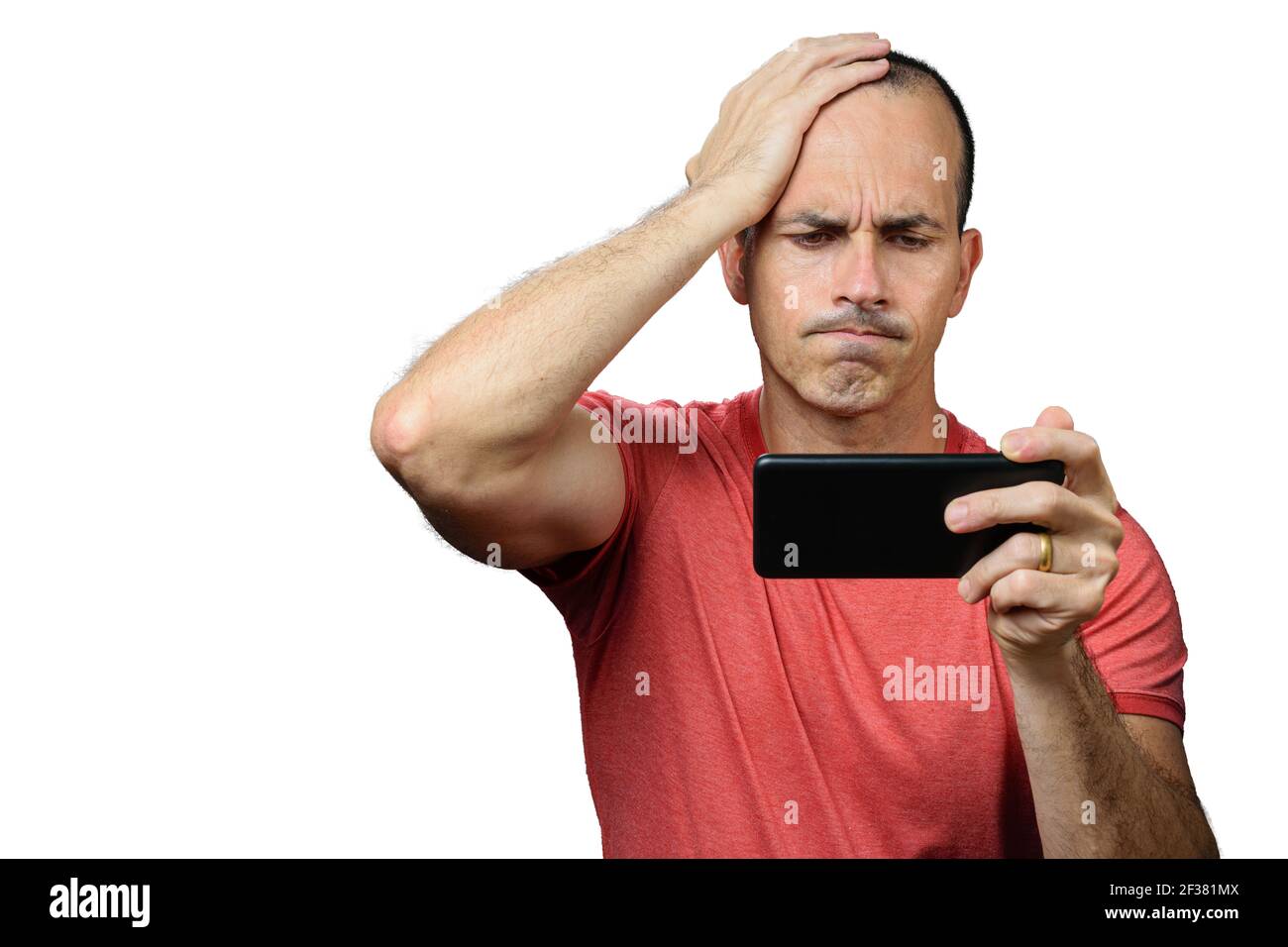 Uomo maturo in abiti casual, deluso, con la mano distesa sulla testa e tenendo lo smartphone orizzontalmente. Foto Stock