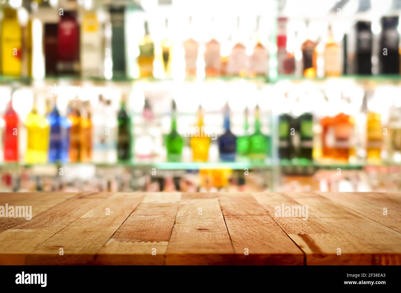 Barra di legno su sfondo colorato sfocato alcol bottiglia di bevande - può essere utilizzato per la visualizzazione o il montaggio dei prodotti Foto Stock