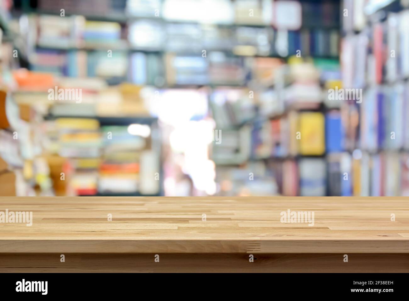 Tavolo in legno sullo sfondo interno del piccolo negozio di libri sfocato - può essere utilizzato per la visualizzazione o il montaggio dei prodotti Foto Stock
