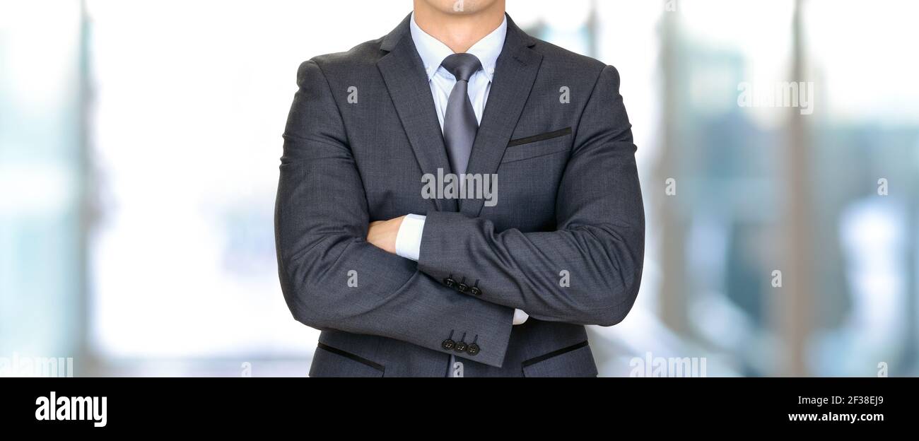 Uomo d'affari anonimo in abito grigio scuro che attraversa le braccia - panoramica header business background Foto Stock