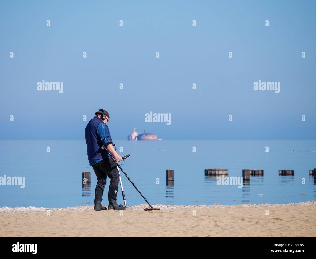 Beachcomber con rilevatore di metalli. Harrison-Dever presa d'acqua presepe in distanza. North Avenue Beach, Chicago, Illinois. Foto Stock