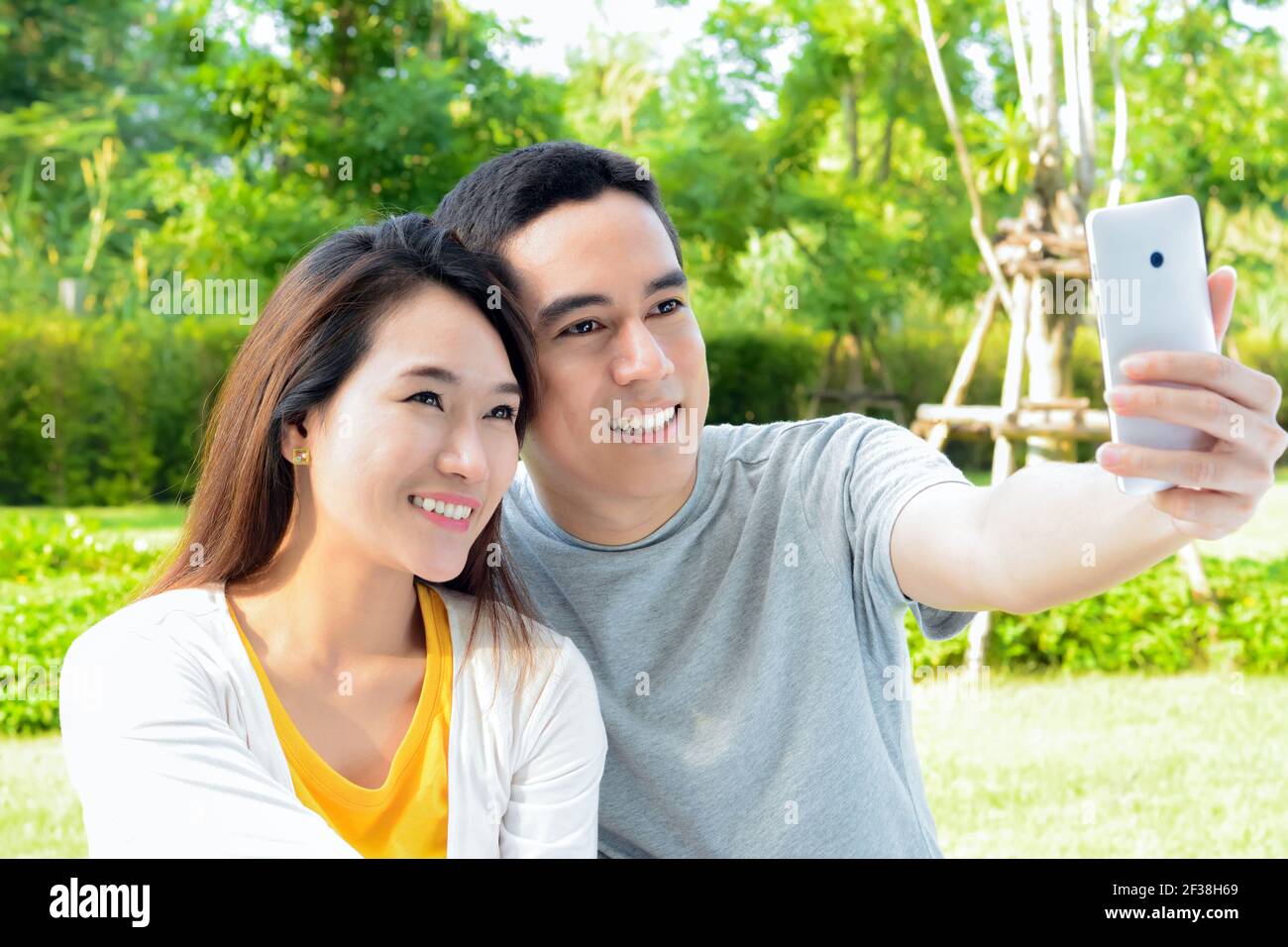 Giovane coppia asiatica che prende selfie nel parco Foto Stock