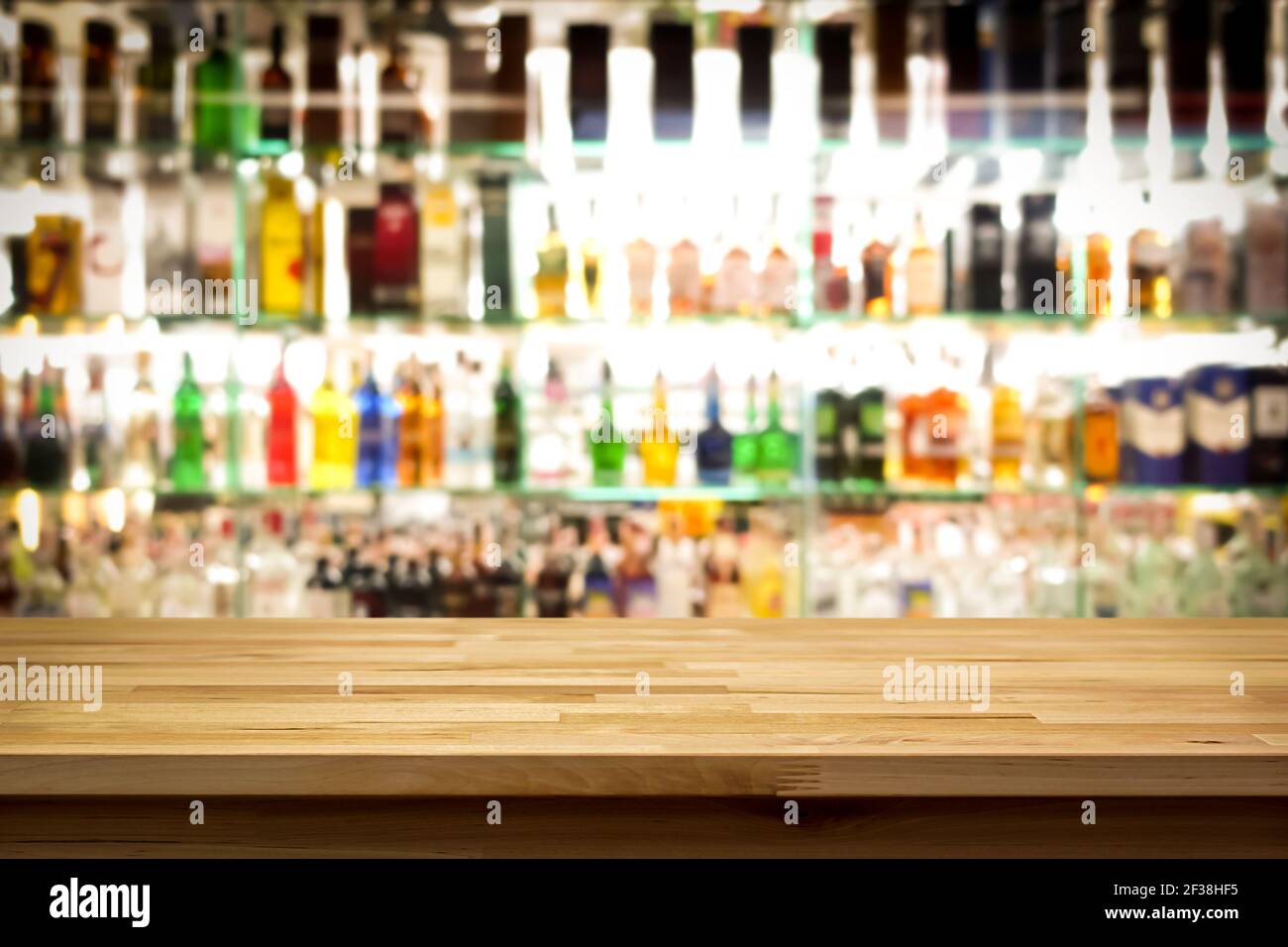 Barra di legno su sfondo colorato sfocato alcol bottiglia di bevande Foto Stock